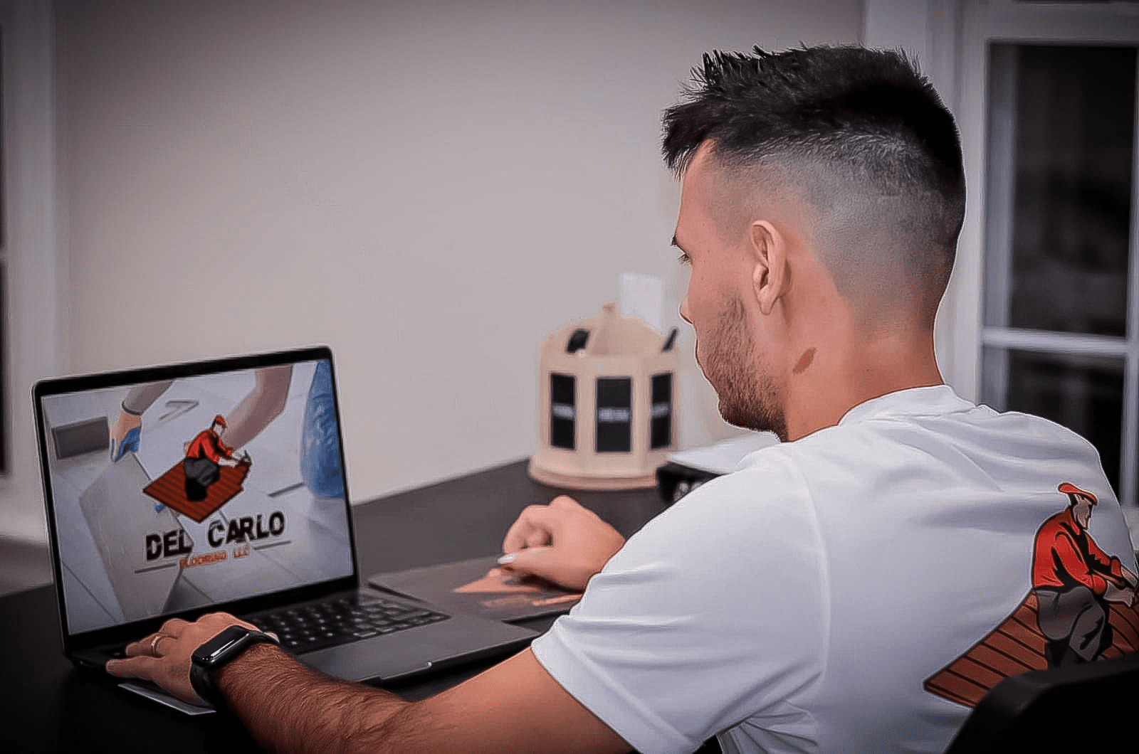 Fúlvio Del Carlo working on a laptop, preparing a project for a Del Carlo Flooring client